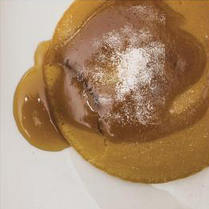 A picture of the cake garnished with caramel sauce and sugar powder